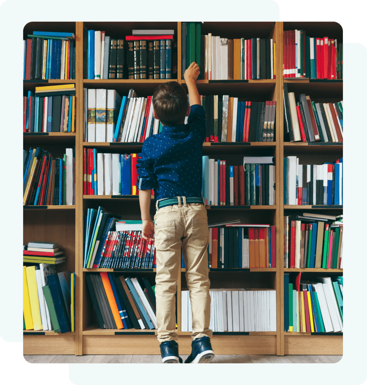 Child reaching for book on tall shelf.
