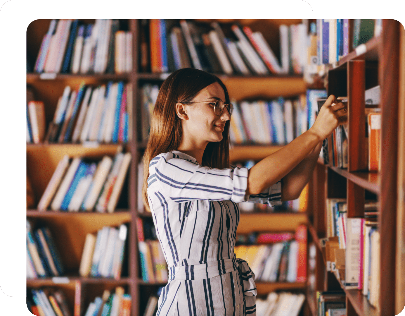 Woman selecting book from library shelf.